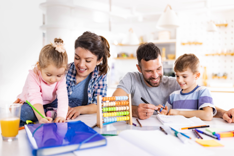 Parents helping their young children with schoolwork at home, using notebooks, pens, and an abacus.